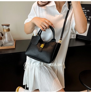 Detail view of black lychee grain leather bucket bag with elegant gold hardware clasp