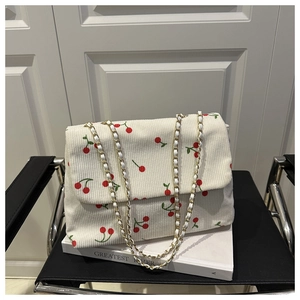 Détail du sac bandoulière en velours côtelé blanc avec motifs de cerises
