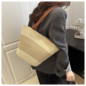 Detail view of woven straw tote bag with brown stripes and durable fabric shoulder straps