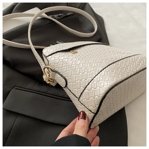 Detailed view of white woven PU leather handbag with black edges and gold hardware zipper