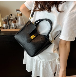Detailed shot of an elegant black lychee textured bucket bag worn as a crossbody