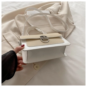 Close-up of a white textured crossbody bag with a beige woven flap and silver metal buckle