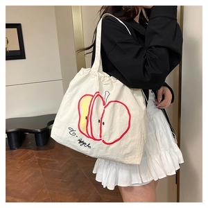 Detail of white nylon tote bag featuring artistic apple print and drawstring closure