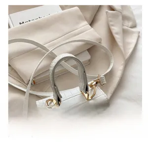 Detail of white crocodile pattern handbag with gold handle and metal clasp closure