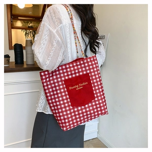 Detail of red gingham canvas tote with embroidery and colorful woven shoulder strap
