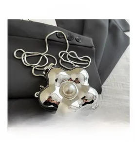 Detailaufnahme der silbernen Blumen-Abendtasche mit zentraler Perle und Schlangenkette