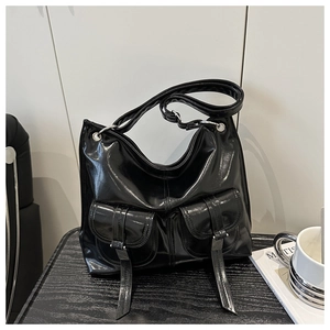 Detail view of black glossy tote bag with twin buckle pockets and silver metal eyelets