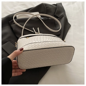 Detail of cream woven textured shoulder bag with black contrast piping and fringe tassel