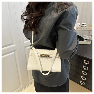 Close-up of white crocodile pattern shoulder bag with a gold metal turn-lock closure