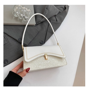 Detail of white sequin shoulder bag with golden clasp and decorative stitching