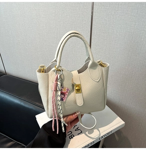 Macro view of elegant white lychee pattern bucket bag with golden twist lock detail