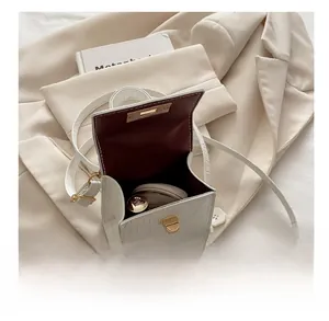 Mini white faux croc handbag detail showing gold twist lock and interior capacity