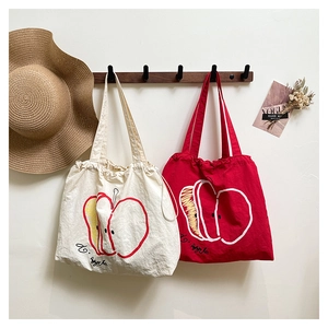 Detail of artistic apple drawing and handwriting text on nylon tote bags in lifestyle setting