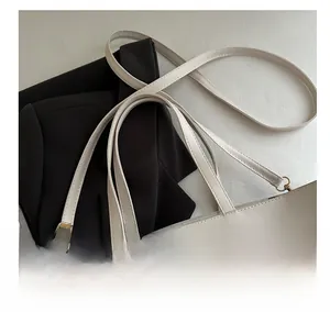 Detail of adjustable shoulder strap and gold buckle on a beige leather tote bag