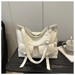 Detail of white glossy tote bag showing front flap pockets and silver metal rings