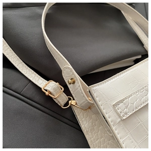 Close-up of white crocodile pattern shoulder bag with golden hardware and detailed stitching