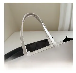 Detailed close-up of smooth white leather tote bag handle with refined stitching