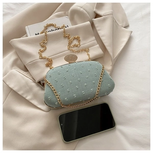 Detail of mint green handbag with textured dots and sparkling rhinestone clasp