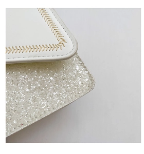 Detailed close-up of white leather stitching and sparkling silver sequins on bag