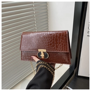 Detailed view of the dark brown crocodile embossed texture and golden metal twist lock