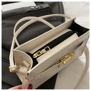 Close-up of white croc-embossed bag interior with zipper compartment and gold hardware