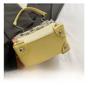 Detail of yellow box bag with leather trim, woven texture, and chunky silver chain link