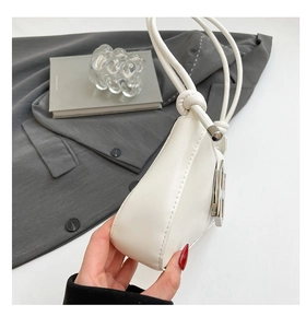 Détail du sac sous le bras en similicuir blanc avec nœud décoratif et boucle argentée