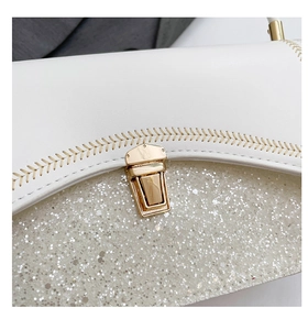 Detail of white leather bag featuring silver glitter panels and gold metal clasp