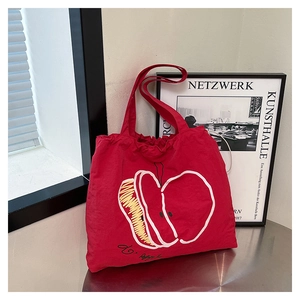 Detail of red canvas tote bag featuring minimalist apple print and sturdy double straps