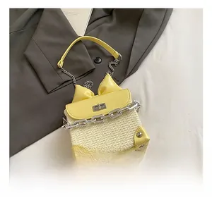Detail shot of mini woven crossbody bag with yellow leather bow and metal chain strap