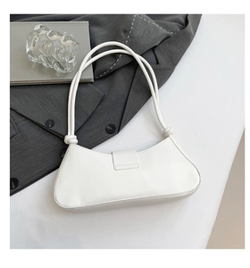 Gros plan sur un sac croissant en cuir PU blanc avec des détails de nœuds sur la bandoulière