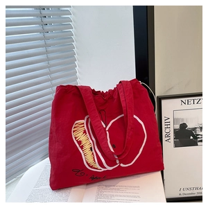 Detailed view of red canvas tote featuring artistic apple print in a lifestyle setting