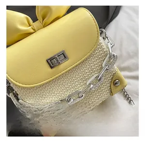 Detail of cute yellow leather bow and silver metal twist lock on a woven mini bag