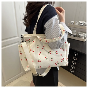 Détail du sac fourre-tout en velours côtelé avec broderie cerise et large bandoulière