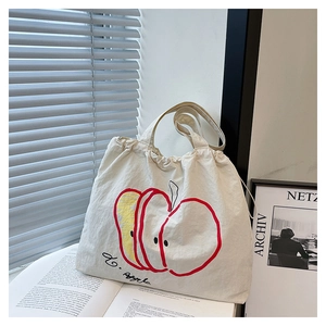 Close-up of beige nylon tote bag with artistic apple print in a minimalist indoor setting