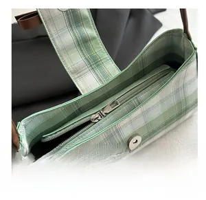 Detailed close-up of smooth zipper closure and fabric lining of green checkered bag