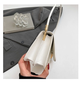 Detail view of white textured leather bag showing dual-compartment design and gold hardware