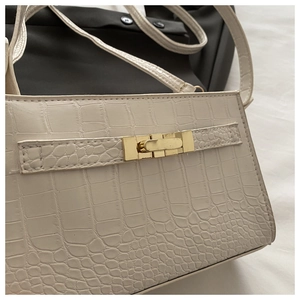 Detail of white crocodile pattern PU leather texture and gold metal clasp on a handbag
