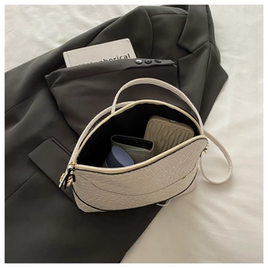 Close-up of woven shell bag interior with items on a gray blazer and white background