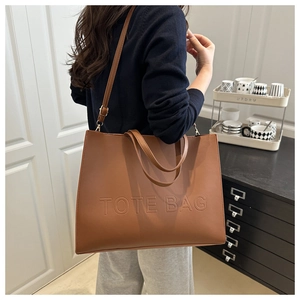 Detail of dark brown leather tote bag showing embossed lettering and detachable shoulder strap