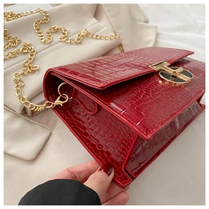 Macro shot of red crocodile embossed leather bag with gold circular buckle detail