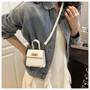 Detail of white crocodile texture on small square bag with golden metallic twist lock