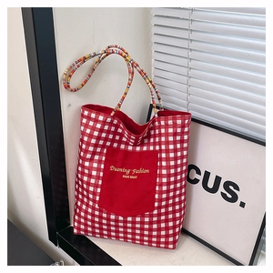 Detail of red and white checkered canvas tote bag with woven handles and large pocket
