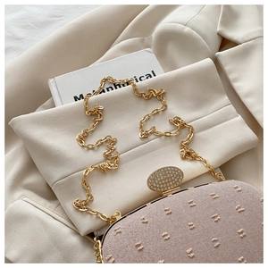 Detail of light pink textured handbag with crystal-encrusted buckle and gold chain strap