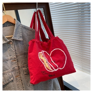 Detail of red drawstring canvas tote bag featuring a white outline apple graphic print