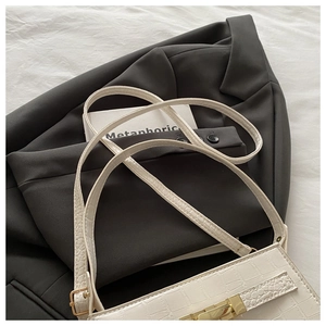 Macro detail of creamy white crocodile pattern handbag with elegant gold rectangular clasp