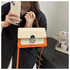 Detail of bicolor crossbody bag featuring woven texture flap and metallic D-ring buckle