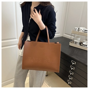 Close-up of dark brown leather tote bag with embossed lettering and twin handles