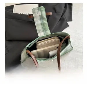 Interior view showing the capacity of the green plaid underarm bag with daily essentials