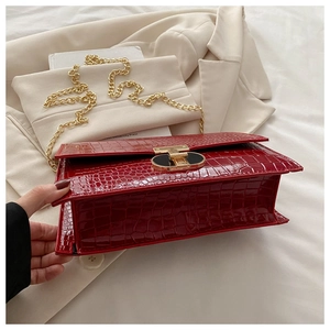 Detail of red crocodile texture handbag with gold chain strap and elegant clasp